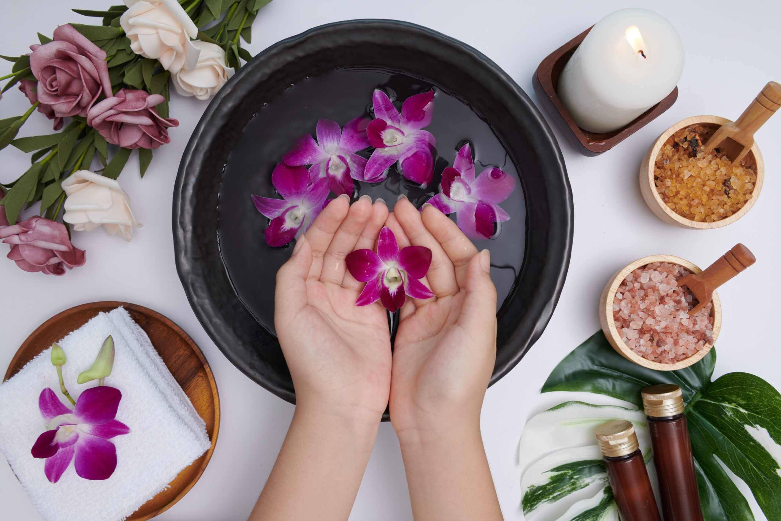 Woman soaking her hands in bowl of water and flowers, Spa treatm